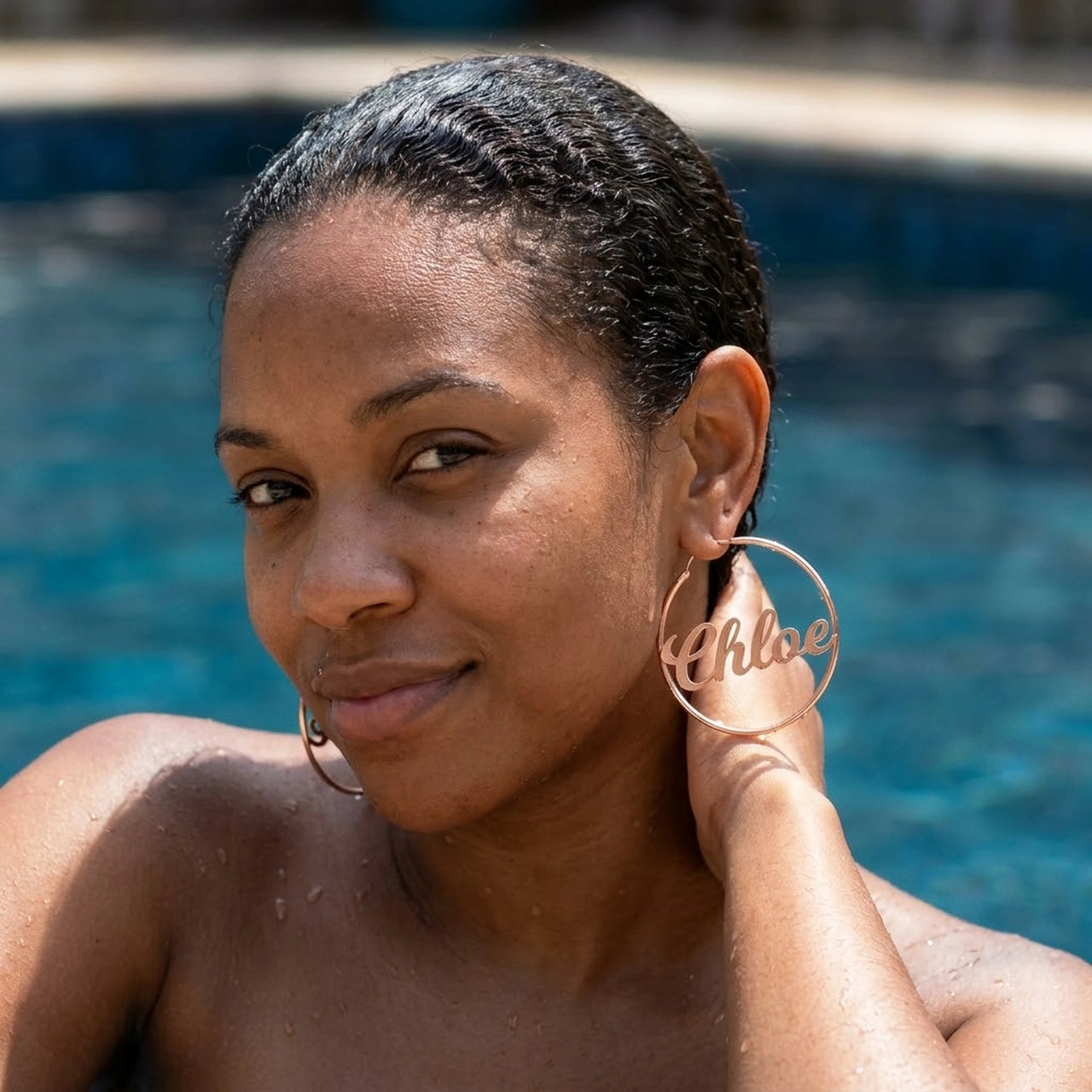 Custom Name Hoop Earrings in Rose Gold worn in a swimming pool, waterproof 304L stainless steel | SKU: name-hoop-rose-gold-30-mm