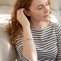 Thumbnail for Woman gently touching her Never Forget To Dream bracelet in silver | SKU: nftd-wg