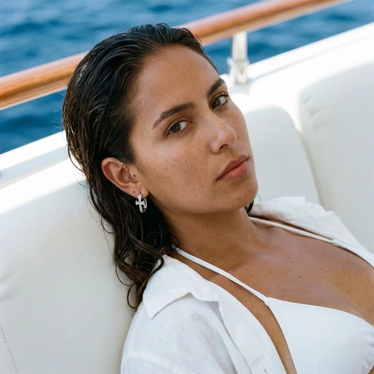 Pave Cross Huggie Hoops in Silver, worn on a yacht | SKU: 41006-silver