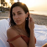 Thumbnail for Pearl Drop Huggie Hoops in Gold, worn at a beach club at sunset | SKU: 41003-gold