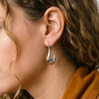 Thumbnail for Sculpted Crescent Drops in Silver, close-up on the earlobe | SKU: 41008-silver
