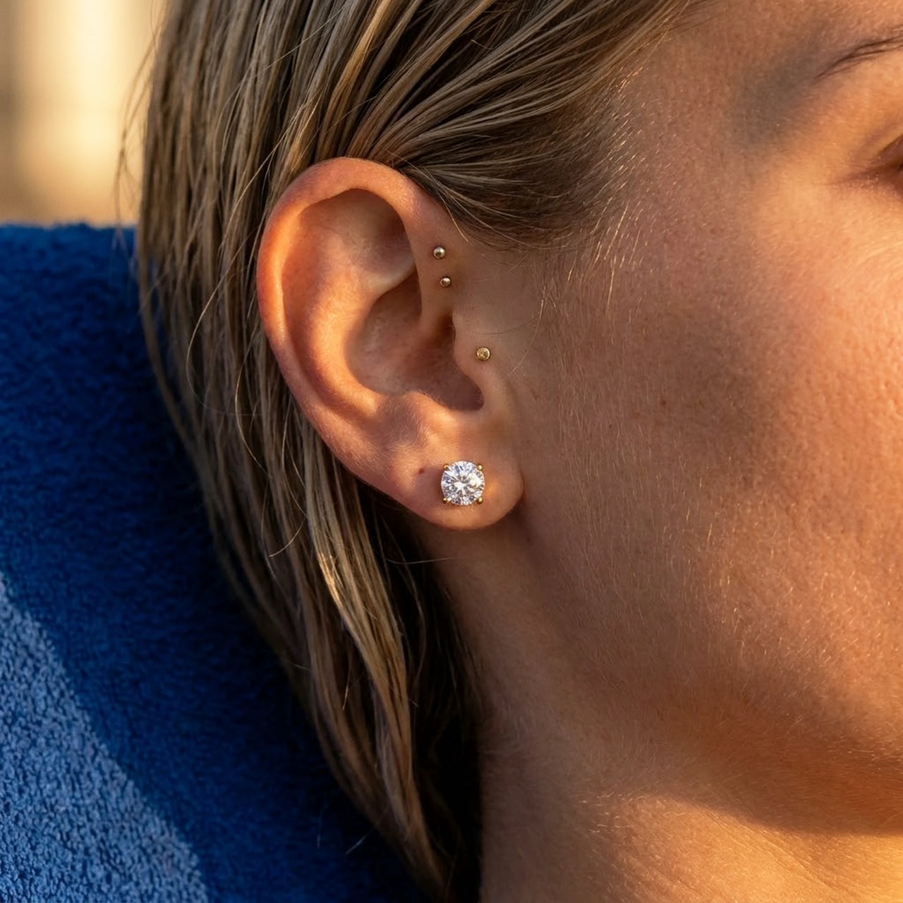 Solitaire Crystal Studs in Gold, close-up on the earlobe | SKU: 41010-gold