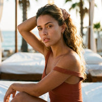 Thumbnail for Tiny Huggie Hoops in Gold, worn at a beach club at sunset | SKU: 41002-gold