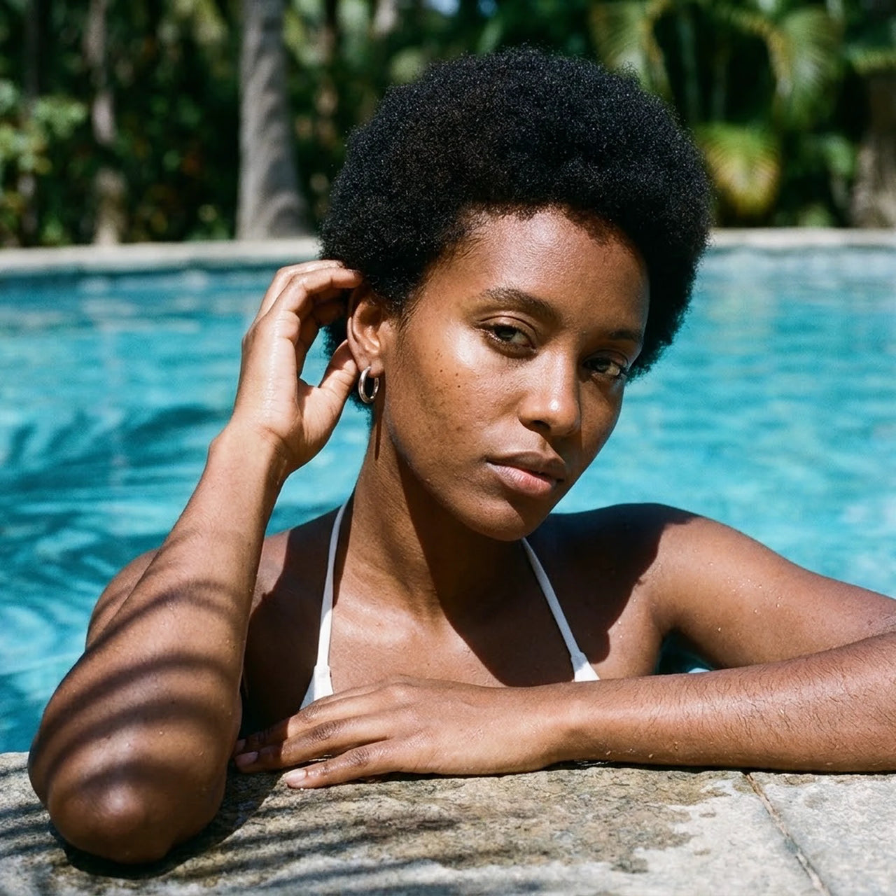 Tiny Huggie Hoops in Silver, worn by a tropical pool | SKU: 41002-silver